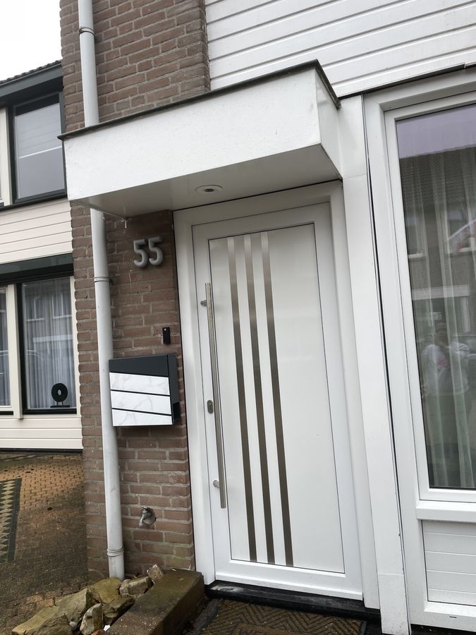De witte voordeur met huisnummer 55